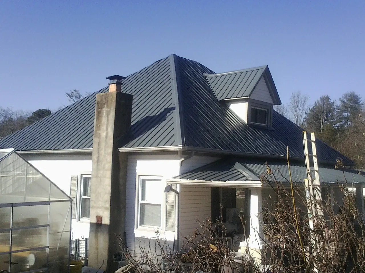 Dark blue standing seam metal roof on a white farmhouse with dormer — Slate & Tile Roof Repair by Roofing Brothers in Platina