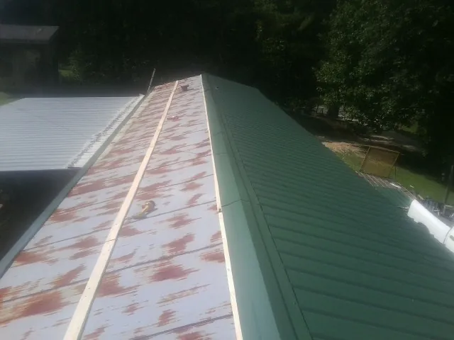 Old rusted panels beside newly installed green metal roofing — Wind Damage Roof Repair by Roofing Brothers in Platina