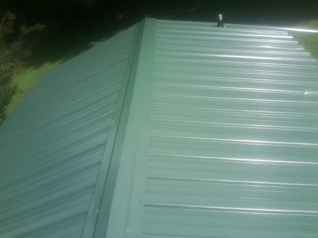 New green metal panels meeting at the ridge of a roof — Flat Roof Repair work by our crew in Platina