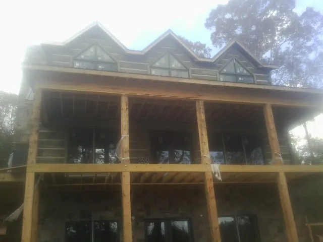 Dormers and porch framing on a large log home under construction — Roof Coating work by our crew in Platina