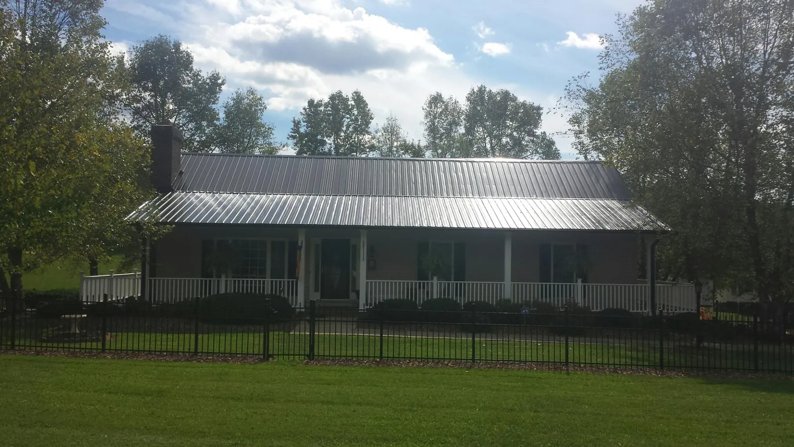 Gray metal roof on a brick ranch with a full width front porch — Gutter Guard Installation work by our crew in Platina
