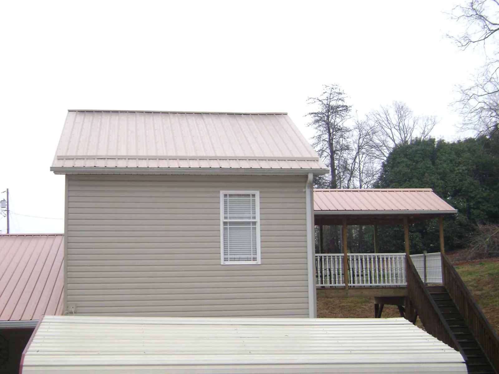 Tan metal roofs on a two story addition and attached porch, from a Roof Replacement job in Platina