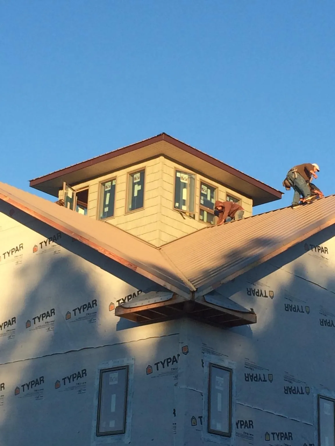 Roofers working around a rooftop cupola on a new metal roof at sunset — Roof Waterproofing in Platina by Roofing Brothers